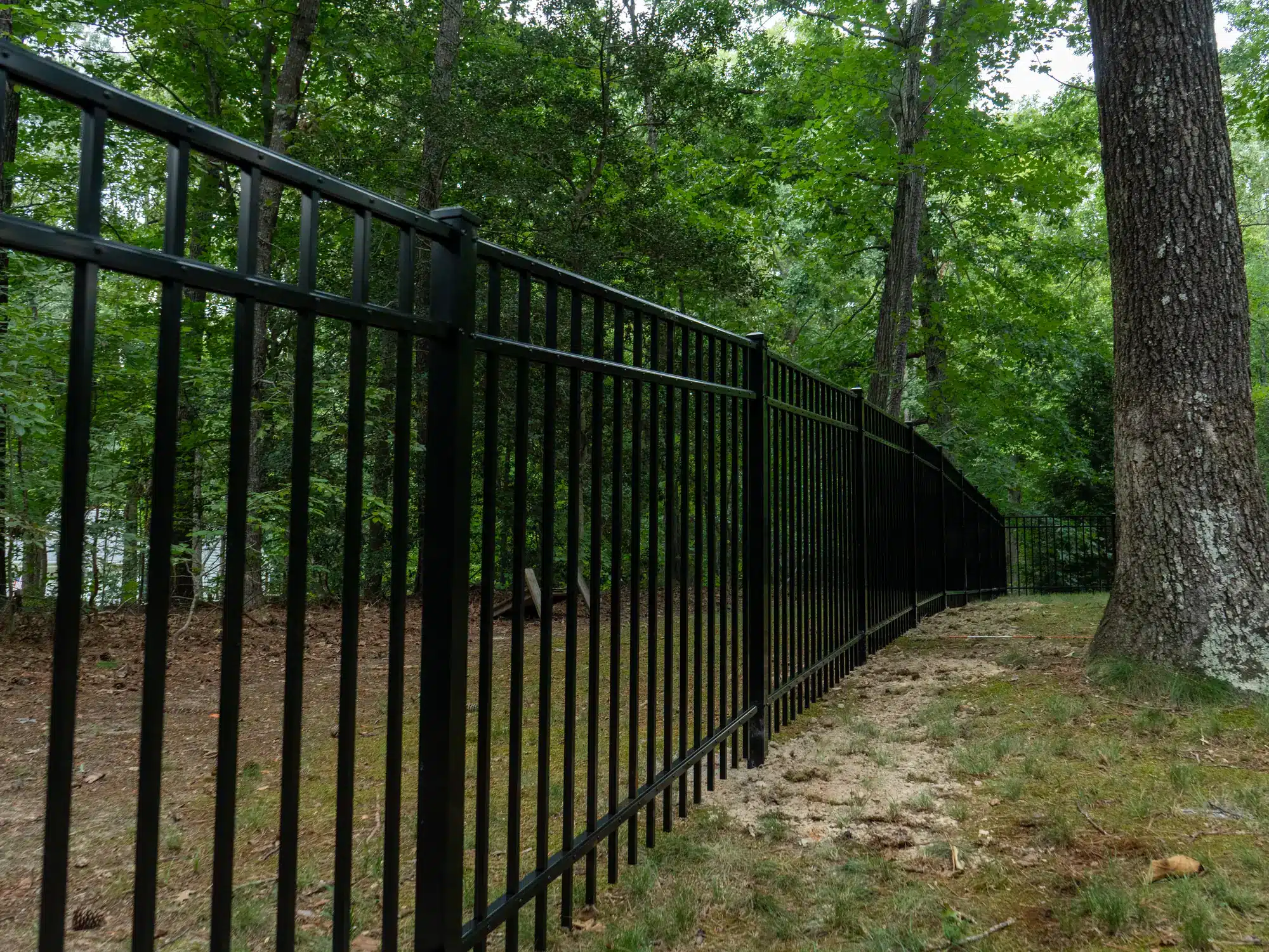 Aluminum fence on a steep slope in Henrico, VA, racked down a wooded hillside