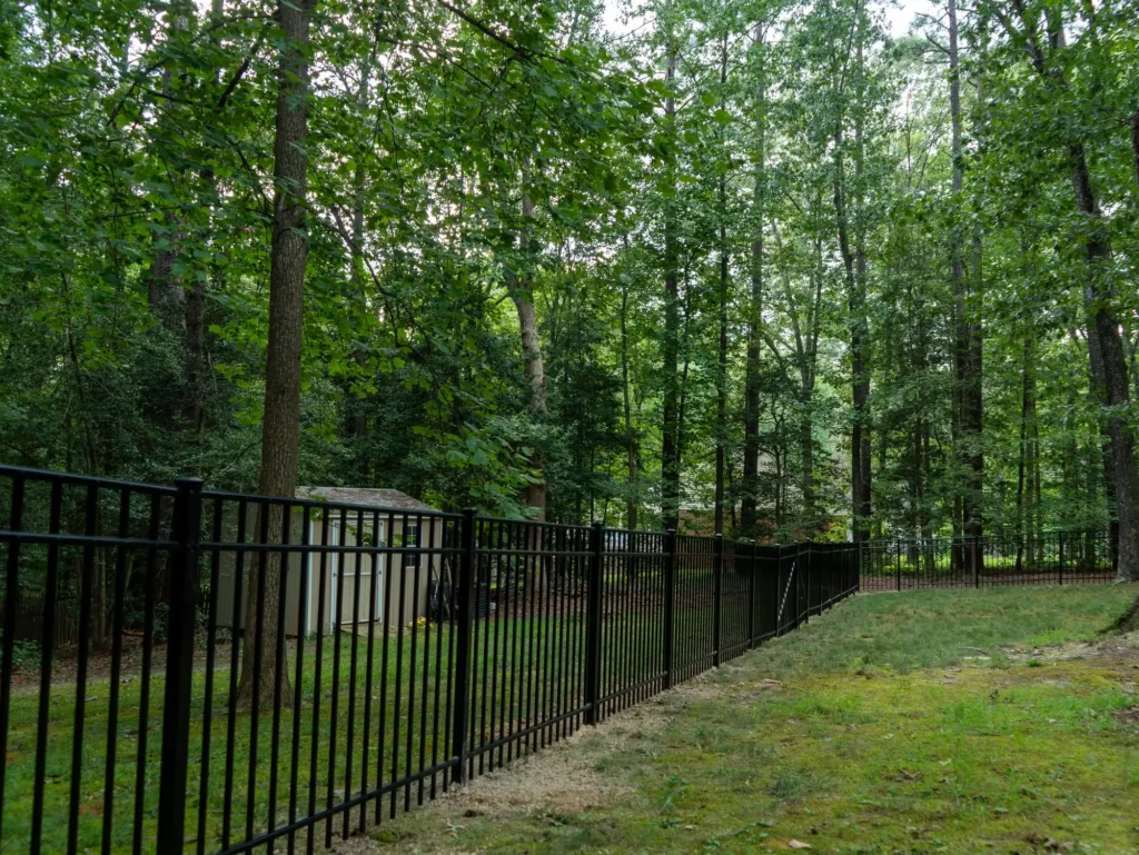 Newly installed black aluminum fence enclosing a wooded backyard in Henrico, Virginia