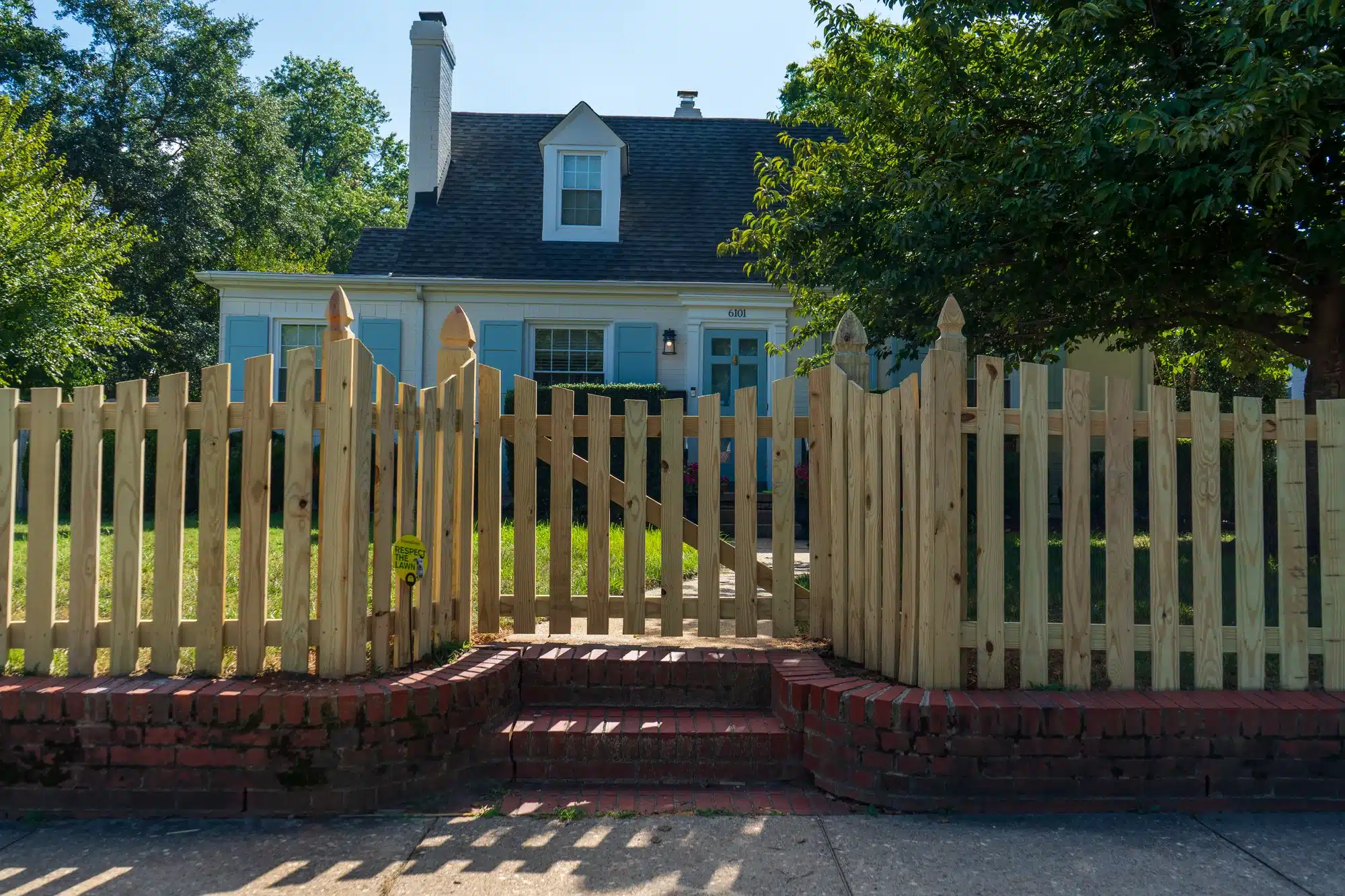 Concave wood picket fence and gate on a low brick wall in front of a Richmond, VA home