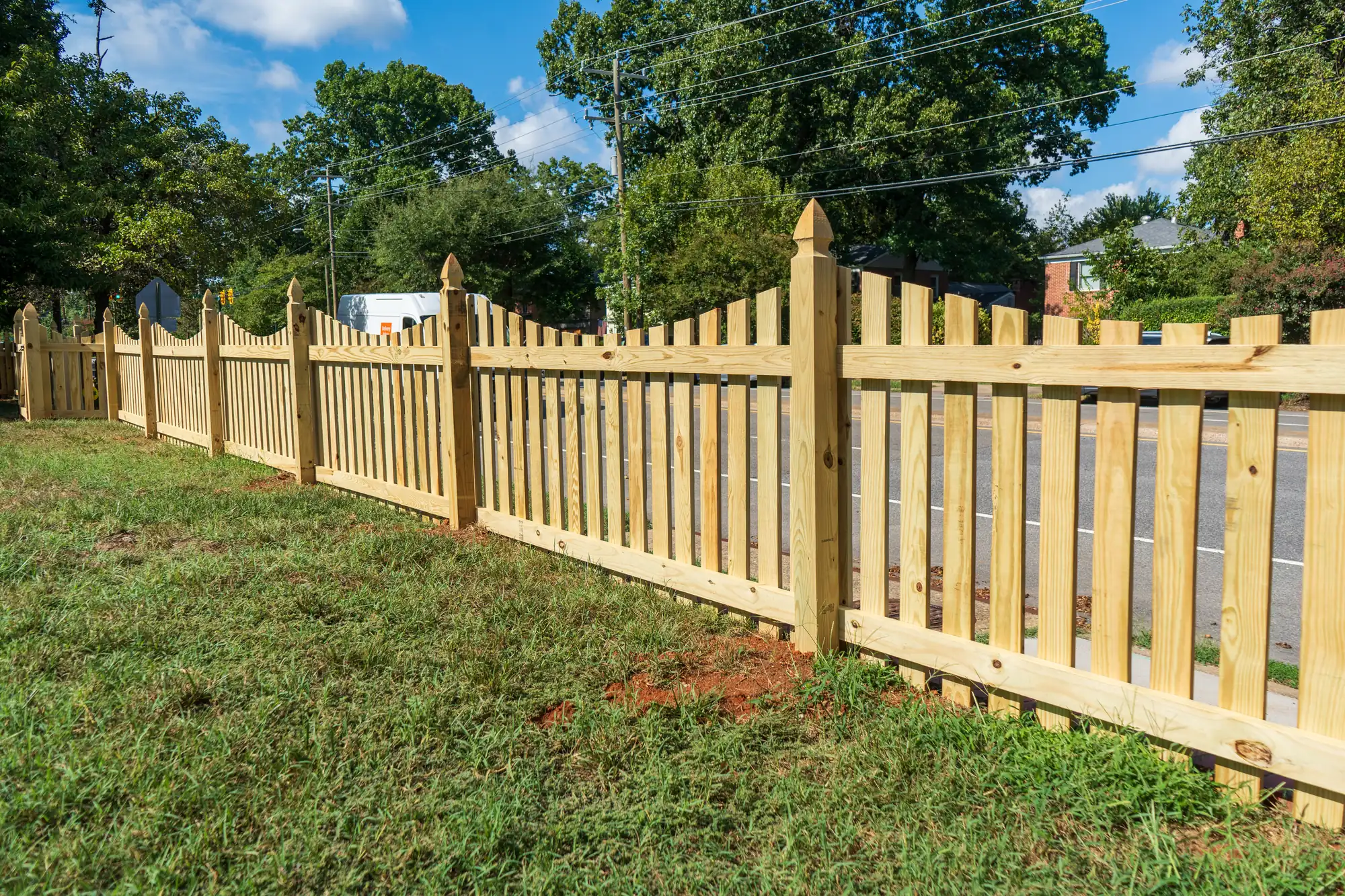 Concave wood picket fence with French gothic posts across a side lawn in Richmond