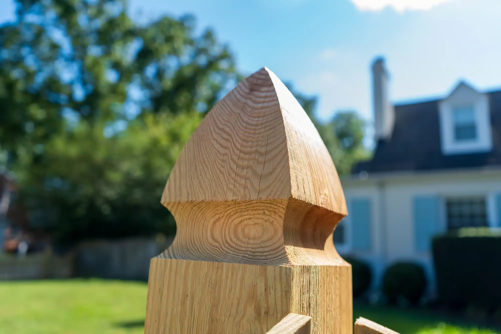 Close-up of a French gothic post top on a pressure-treated wood fence