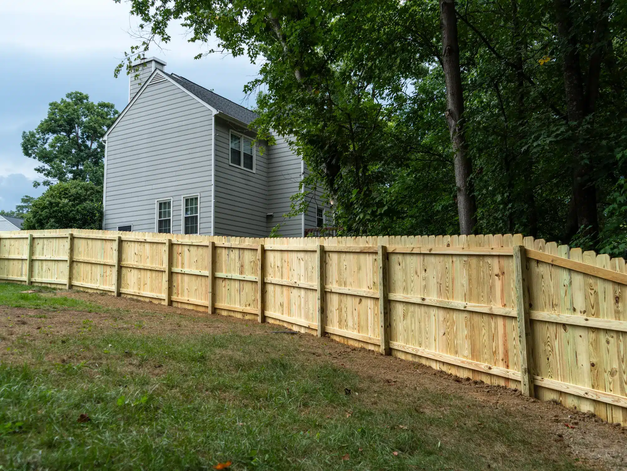 Wood privacy fence stepping down along a sloped Short Pump backyard