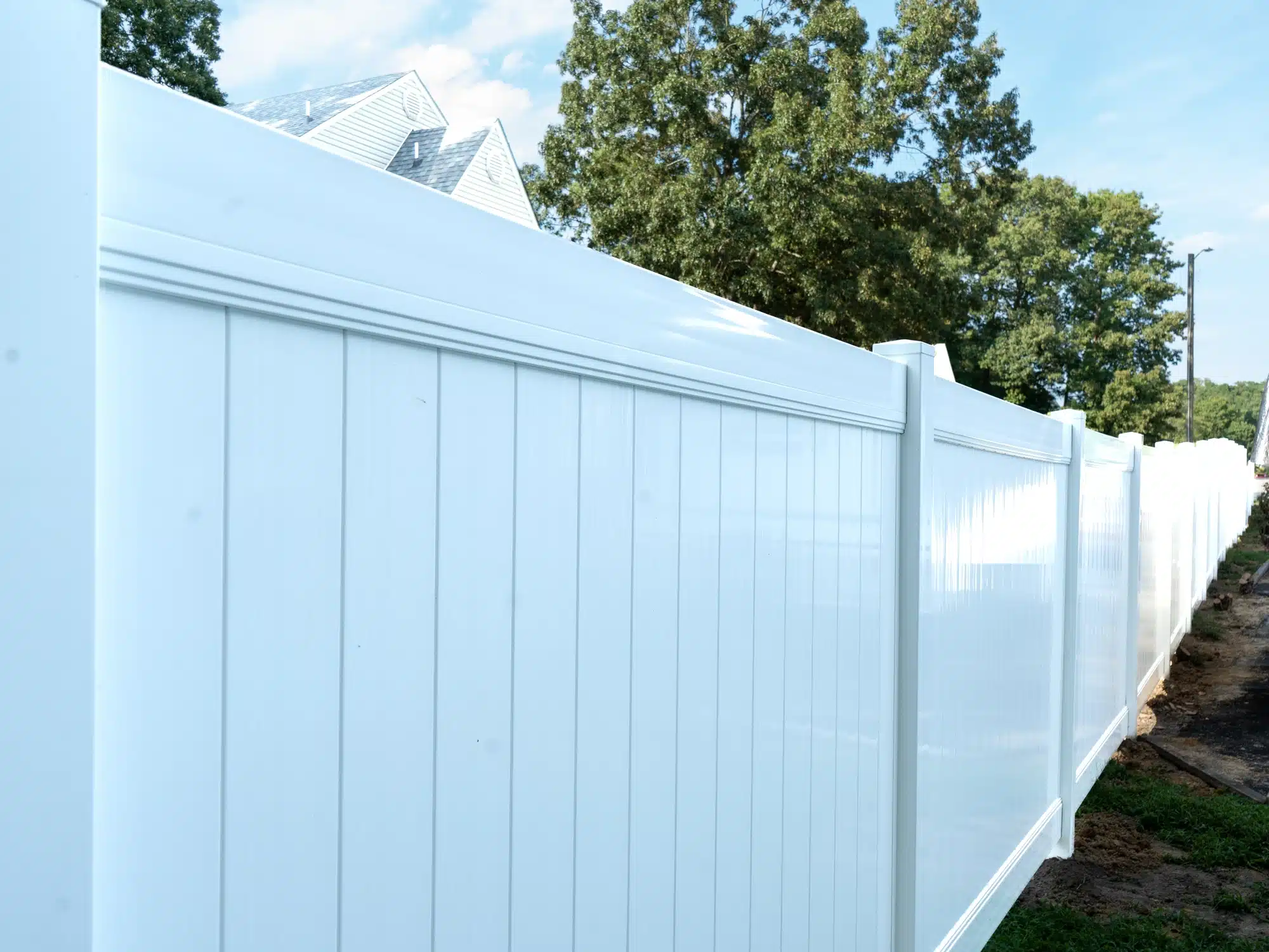 Close-up of vinyl fence parts on a Hopewell privacy fence: white posts, top rail and panels