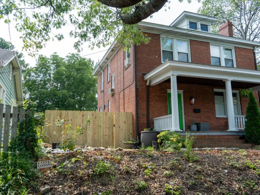New unstained wood privacy fence beside a red brick foursquare home in Richmond, VA