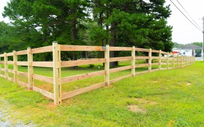 Pressure-treated 4 board paddock fence curving across a green pasture